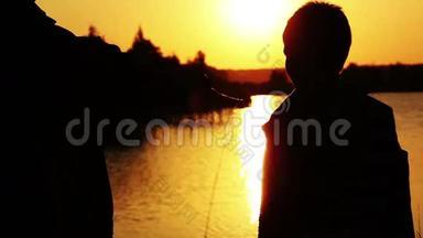 日落时分，母亲抱着儿子在河边，<strong>夕阳余晖</strong>映在水面上